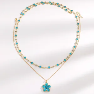 Detailed view of a gold layered necklace featuring a blue flower pendant and crystals