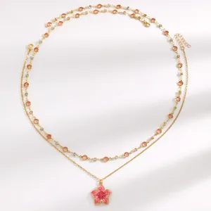 Detail view of double-layered necklace with pink enamel flower and crystal accents