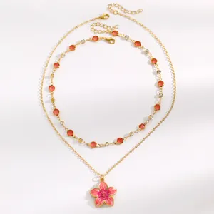 Close-up of sweet pink enamel flower pendant and vibrant red crystal chain necklace