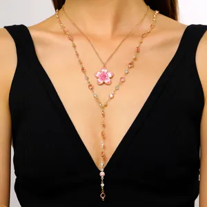 Detail view of a pink enamel flower pendant with a colorful crystal chain