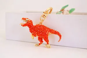 Detailed view of an orange rhinestone T-Rex dinosaur keychain with gold metal frame
