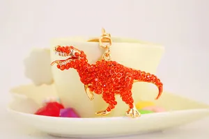 Close-up showing the sparkling orange rhinestone texture on a golden dinosaur keychain