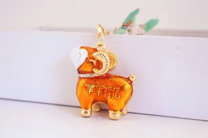 Vue détaillée d'un mignon porte-clés mouton du zodiaque en émail orange avec strass.