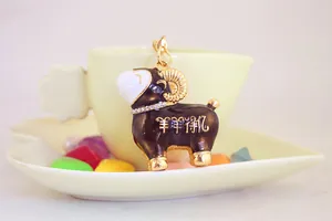 Détail d'un porte-clés mouton en émail brun avec strass et texte chinois porte-bonheur