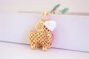 Détail d'un joli porte-clés mouton doré avec motif évidé et tête en émail blanc élégant.