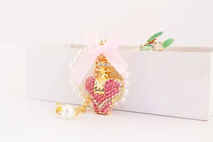 Detailed close-up of pink crystal perfume bottle keychain with a silk bow and pearl chain