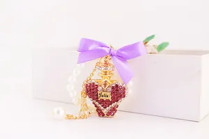 Detailed close-up of a crystal-studded perfume bottle keychain with a purple ribbon bow.