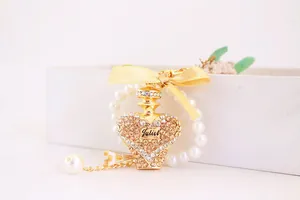 Close-up of heart-shaped perfume bottle keychain with crystals, yellow bow, and pearls