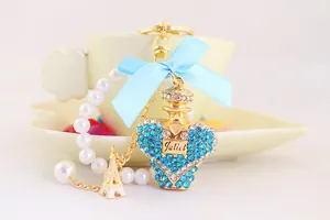 Macro detail of luxury crystal perfume bottle keychain with blue bow and white pearl strap