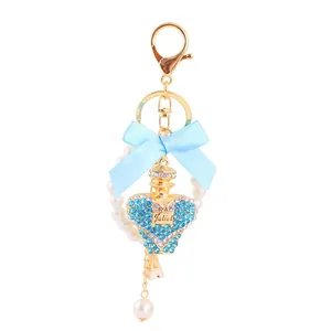 Detailed view of a crystal perfume bottle keychain with a light blue ribbon and pearls