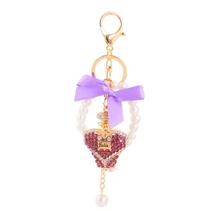 Exquisite heart perfume bottle keychain with purple bow and crystals on white background.