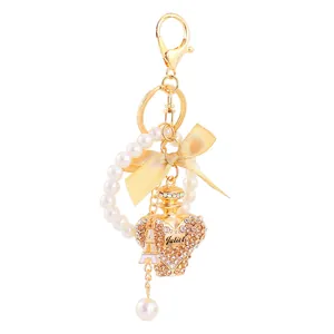 Detail of gold keychain with crystal heart perfume bottle and pearl ring charm