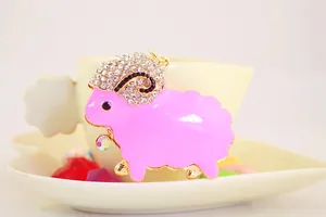 Detailed macro shot of a pink enamel sheep pendant with sparkling white crystals details