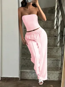 Stylish pink two-piece set featuring a bandeau top and drawstring wide-leg trousers on stairs.