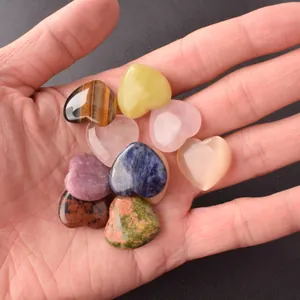 Close-up view of various 20mm heart-shaped natural crystal stones held in a palm.