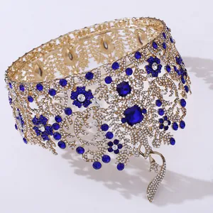Close-up detail of ornate golden Baroque pageant crown featuring blue crystals.
