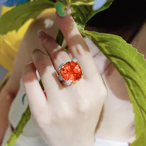 Luxury asscher cut orange gemstone flower ring shown on a model hand with green leaves