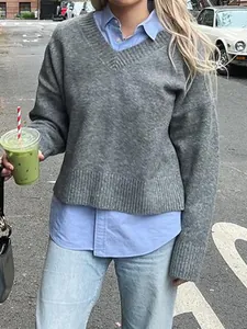 Detailed view of a women's grey V-neck knit sweater layered over a light blue collared shirt