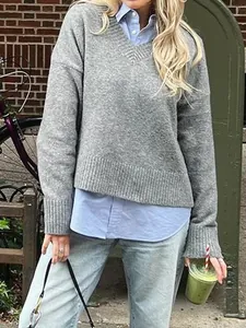Close-up of a grey v-neck knit sweater layered over a light blue long-sleeved shirt