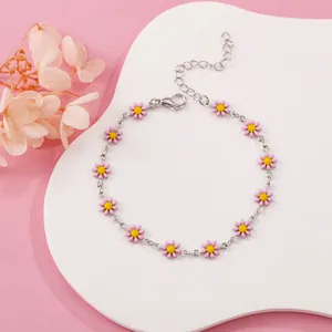 Close-up of a silver chain bracelet with pink enamel daisy flower charms.