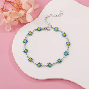 Detail view of a dainty blue and yellow daisy flower chain bracelet on white display