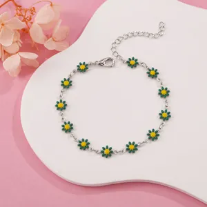 Close-up of silver-tone chain bracelet with green and yellow enamel daisy charms.
