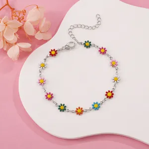 Detailed shot of a colorful daisy charm bracelet with silver chain on a white plate