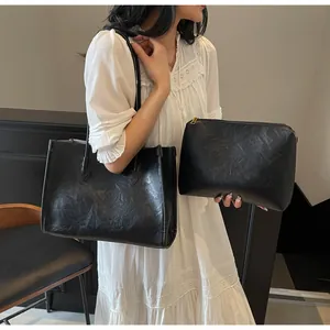 Detailed shot of the black vintage tote bag and pouch set held by a model in white dress