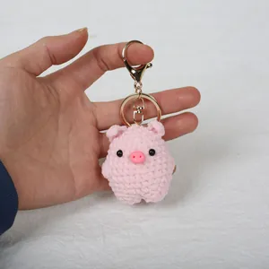 Handmade crochet pink pig keychain pendant held by hand showing detailed texture.