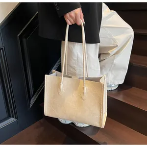 Large beige tote bag with unique crinkled leather texture held by a model on stairs