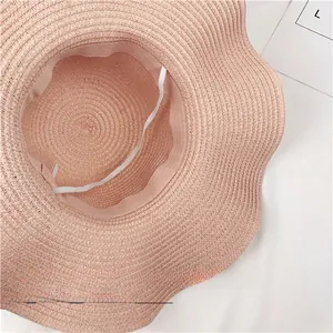 Close-up detail of a pink foldable straw sun hat showing the inner elastic strap