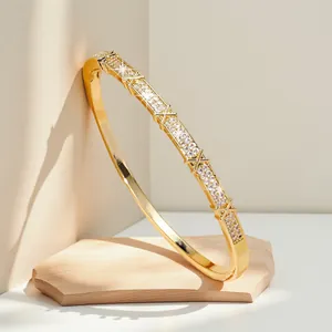 Elegant gold-plated bangle with pavé zircons and geometric X-pattern detail.