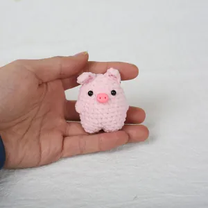 Handmade pink crochet pig animal keychain pendant shown being held in a person's palm