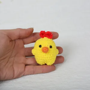 Handheld close-up of a cute yellow handmade crochet chick animal bag keychain pendant