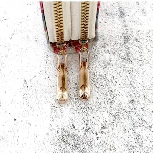 Detailed macro view of dual light gold metal zippers on a luxury card holder wallet