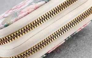 Detailed close-up of high-quality smooth golden metal double zippers on a floral wallet