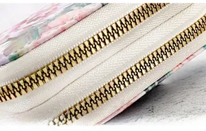 Detailed close-up of high-quality smooth golden metal double zippers on a floral wallet