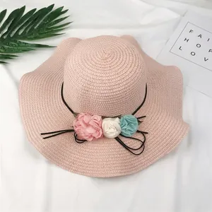 Pink foldable wide brim straw sun hat with decorative flowers for summer beach trips