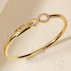 Close-up detail of golden light luxury bangle with infinity symbol and LOVE engraving