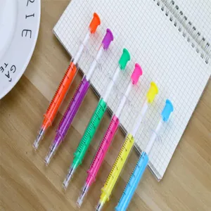 Detailed macro view of six vibrant syringe-shaped creative gel pens on a grid notebook