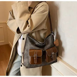 Detailed view of a vintage denim texture hobo bag featuring brown leather pockets.