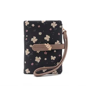 Close-up of a floral printed women's bifold wallet featuring a gold leaf buckle
