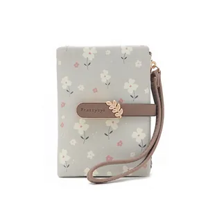 Detail view of a floral printed folding wallet with a gold leaf buckle and wrist strap.