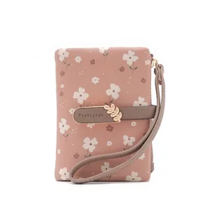 Detailed view of a pink floral wallet with a stylish strap and gold leaf clasp.