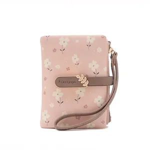 Pink floral printed short wallet for women with leaf buckle and wristlet strap.