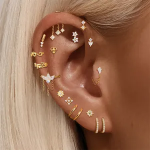 Detailed close-up of gold-toned cartilage piercing studs with sparkling crystals