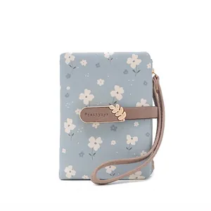 Detail shot of a light blue women's short wallet with white floral print and leaf buckle