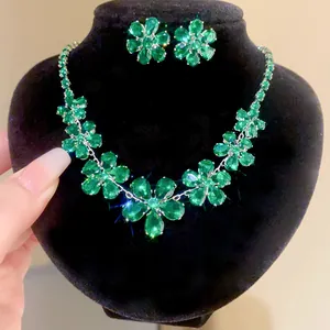 Detailed view of green crystal flower necklace and earring set on black display