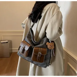 Detail of a denim texture canvas shoulder bag worn with a beige coat, large pockets.