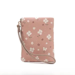 Detailed view of the floral print and wrist strap on this pink short folding wallet.
